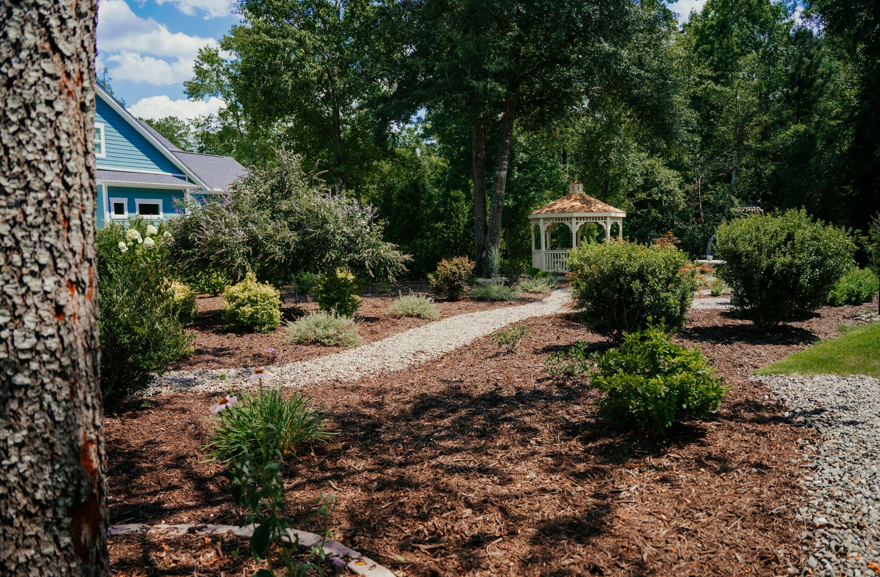 A river-rock path curving through a shade garden toward a gazebo.