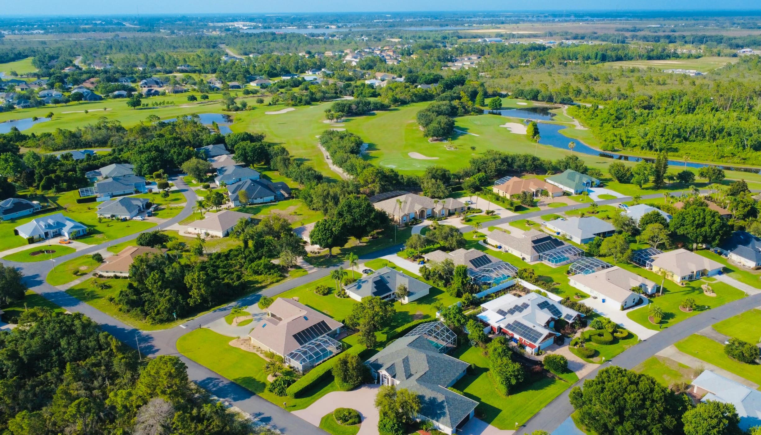An aerial view of a developed residential community with streets, homes, and mature landscape.