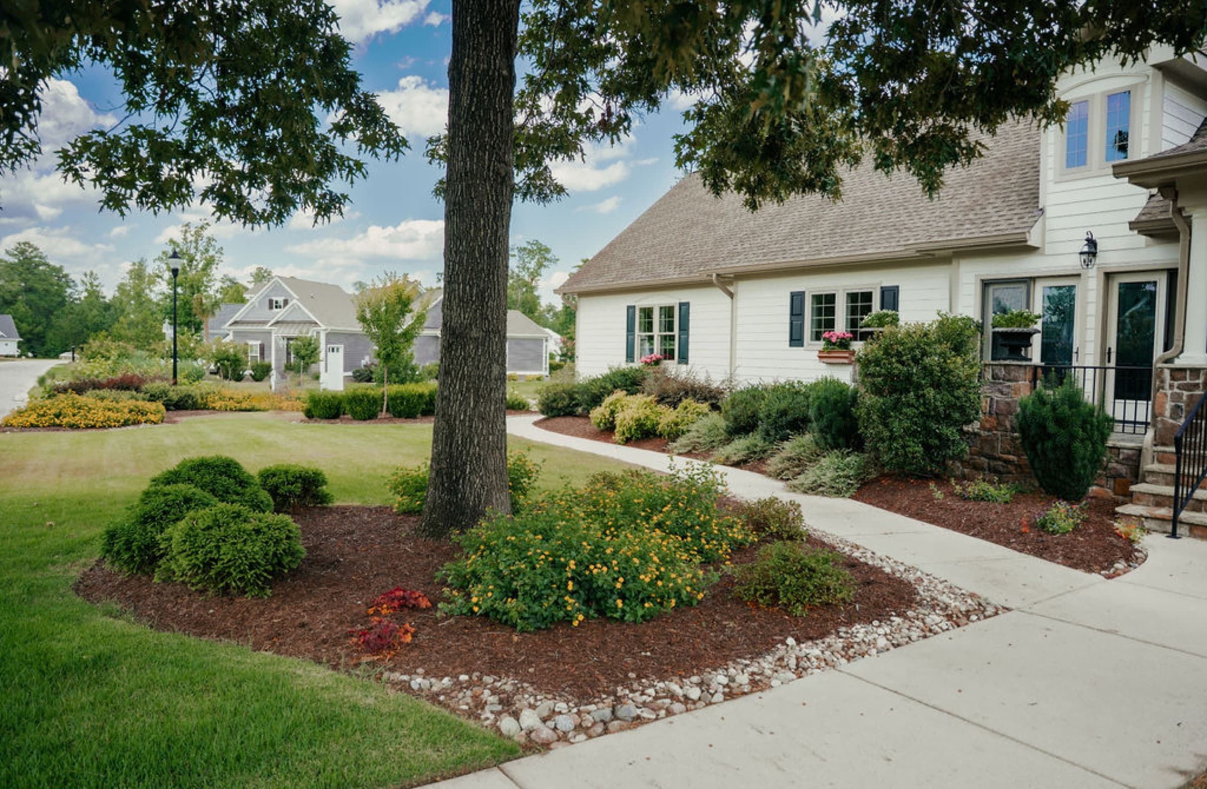 A landscaped home with a curved walkway and full planting beds.